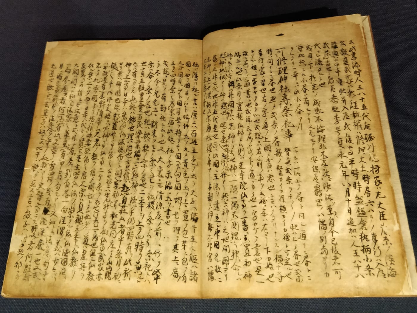 13세기 일본 무사 법전인 고세이바이 시키모쿠의 낡은 필사본 사본이 붓글씨로 쓰인 두 페이지에 걸쳐 펼쳐져 있다.