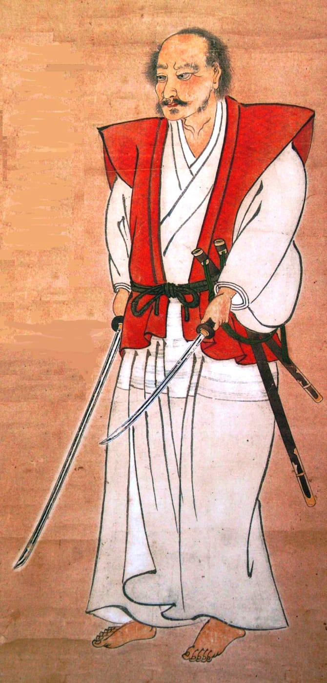 A painted portrait of Miyamoto Musashi standing with a long and short sword drawn in the two-sword stance.