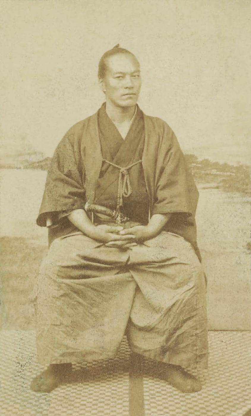A sepia albumen photograph of Yamaoka Tesshū, seated in kimono and hakama, from around the 1860s.