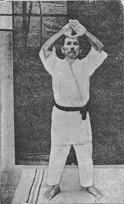 A black-and-white photograph of Gichin Funakoshi demonstrating a karate kata.